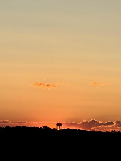 The sunset a moment later with the sun almost completely below the horizon just under the water tower
