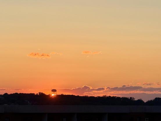 A landscape view of the sunset with a water tower in the left third of the image