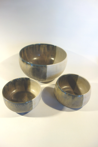 Eine Salatschüssel und zwei kleinere Schalen, 2/3 jeder Schale ist blau-braun-grün glasiert und 1/3 weiß