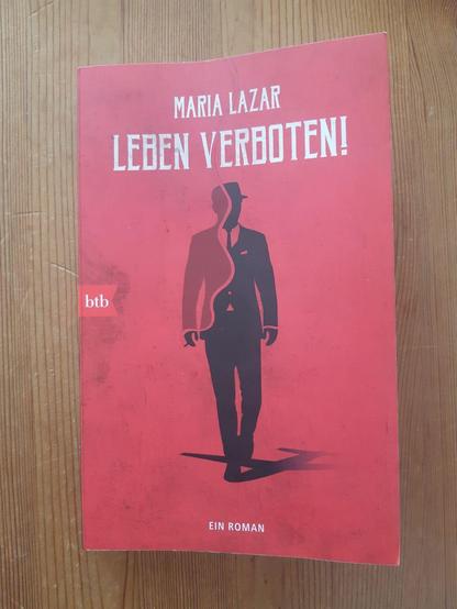 Buchcover in rot. In der Mitte die Darstellung eines Mannes in schwarzem Anzug, der auf die Betrachterin zuzugehen scheint, mit Hut und Zigarette in der locker herabhängenden rechten Hand. Text darüber: Maria Lazar - Leben Verboten! 
In der Mitte links neben dem Rücken die Verlagsangabe: btb 
Text ganz unten Mitte: Ein Roman