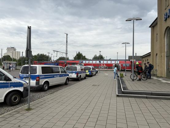 Polizeiwagen vor Bahnhof, Zug im Hintergrund 