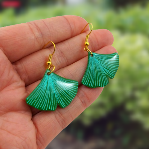 Boucles d'oreilles fantaisie pendantes éco-responsables en forme de feuilles de ginkgo vertes aux nervures vertes métallisées.
Les perles sont réalisées en CD recyclé, découpées et peintes à la main, puis recouvertes de résine époxy.
Les attaches sont en laiton doré, mais sont aussi disponibles dans d'autres métaux et coloris.