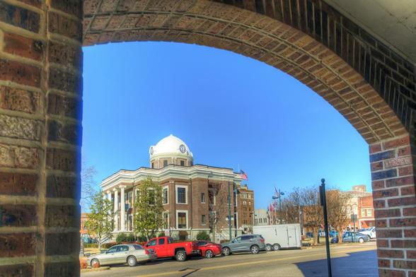 An archway frames a street view of a historic courthouse with a distinctive dome, showcasing classic architecture 