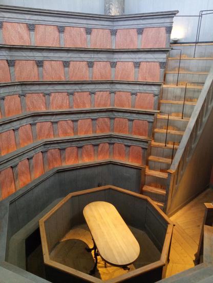 Anatomical theatre. Five rows of audience stands, rising steep, painted in red end blue colours. At the bottom and in the middle of the octagonal room an oval table where, back in day, the cadaver was placed for educational examination.