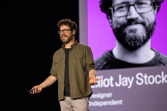 Elliot Jay Stocks talking on stage at Config 2025 in San Francisco, with the screen showing his slides behind him.