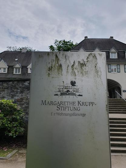Haupteingang der Margarethenhöhe mit einer Infotafel: "Margarethe Krupp-Stiftung für Wohnungsfürsorge".