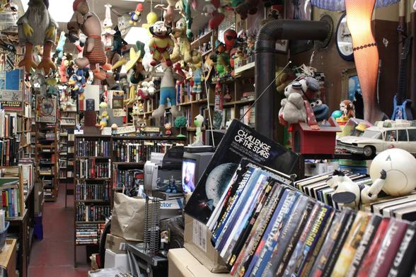 A colorful photo inside Bonnett's Bookstore showing an aisle with thousands of books and a portion of the vast toy collection displayed on shelves and hanging from the ceiling.