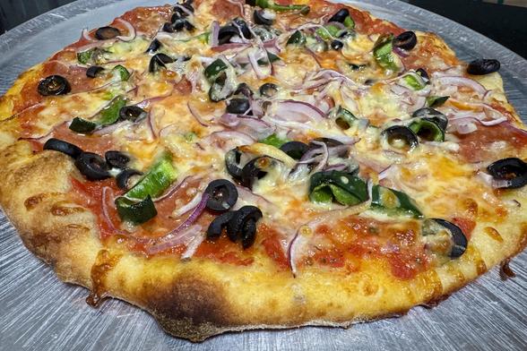 Cooked homemade pizza on a metal pizza pan fresh out of the oven.