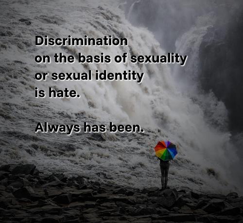An image of a person standing next to a waterfall. The person is mostly hidden by an umbrella that resembles the colours of a rainbow, which typically is seen as a synonym for gay rights and LGBTQIA+ rights. Over that image, the following text is written: "Discrimination on the basis of sexuality or sexual identity is hate. Always has been."
