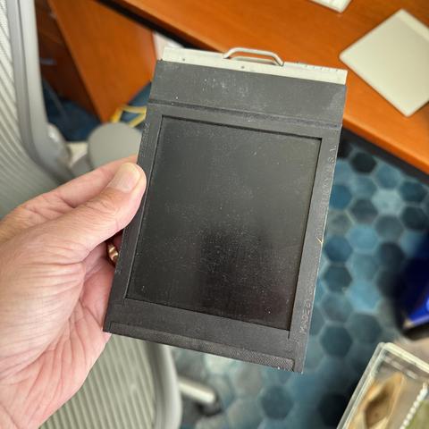 A hand holding a vintage wooden film holder.