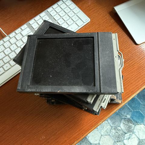 A stack of vintage wooden film holders piled in a desk.