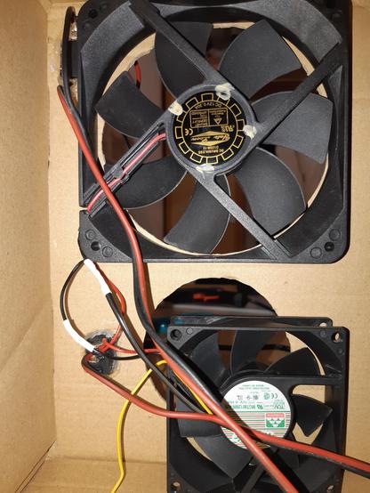 The inside of the DIY solder fume extractor. It shows two fans (the upper one is already connected to the side of the box), two switches from the back, and a lot of messy wiring (soldered connections are covered by heatshrinks).