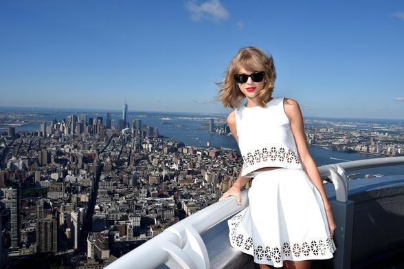 Taylor Swift standing on the Empire State Building with New York behind her