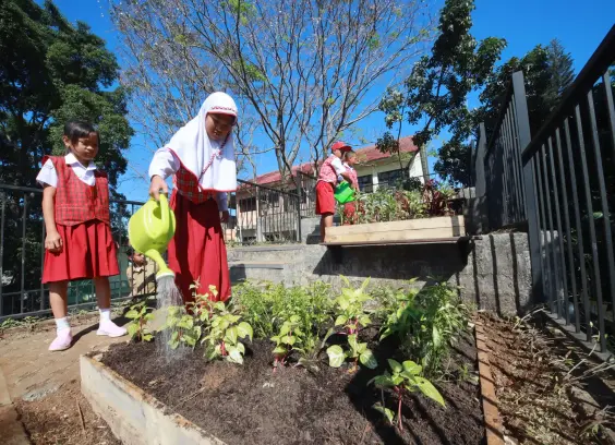 Children watering plants in a rooftop garden.