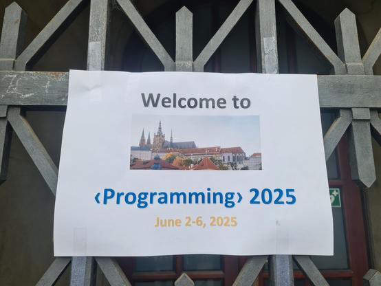 A photo of a Poster saying: Welcome to <Programming> 2025 June 2-6 2025.
There is a picture of Prague on the poster.