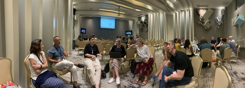 Panoramic picture of a room with people working in groups. 