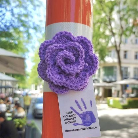 a knittet purple rose in Vienna with a sign Stop Violence Against Women