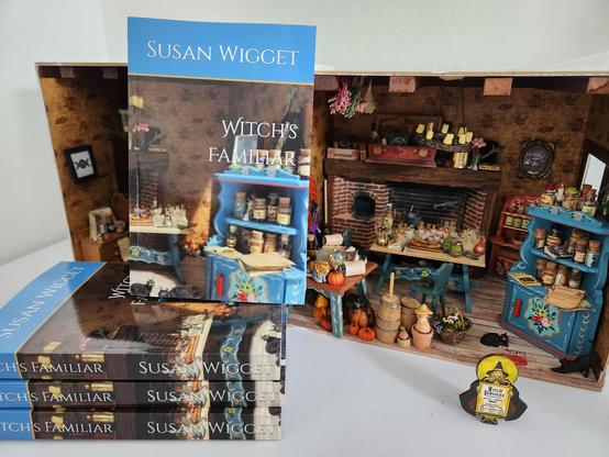 A stack of my book Witch's Familiar and Other Stories with the miniature witch room (1:12 dollhouse scale) that illustrates the cover