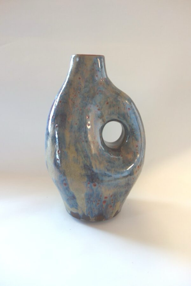 Ovale Vase mit Aushöhlung in der rechten Hälfte. Blaubeige Glasur mit dunkelroten Einschlüssen.
