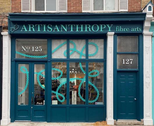 Dark teal storefront with the logo Artisanthropy Fibre Arts across the top.