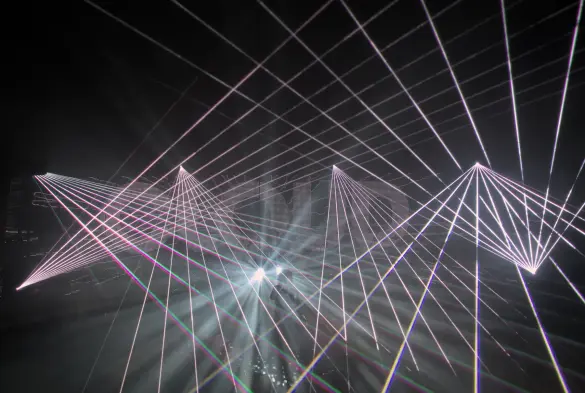 Intertwined white laser contrasting with the darkness around make the photo appear to be geometrical patterns in black and white.