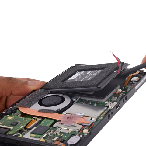 Nintendo Switch being held above a white background with its back cover removed, exposing its internals. On the right another hand is using a spudger to pry the battery up from its cut-out in the console.