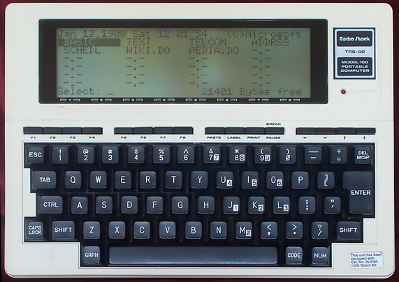 It's a Radio Shack TRS-80 Model 100 portable laptop from the late 80s.  It has a full travel keyboard and a 8 lines x 40 character black and white LCD display.