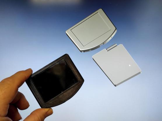 The LCD case in black 3D-printed material in front of the CAD screen showing the combo of LCD and battery housings as it has been conceived.