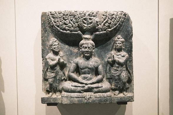 The gods Indra and Brahma entreat the Buddha to deliver his first sermon, Pakistan, Gandhara, 1st c., schist. According to early Buddhist narratives, following his awakening, Siddhartha Gautama initially refrains from teaching, concerned that the depth of his insight (prajñā) may be difficult to grasp. However, heavenly beings — represented here by Indra and Brahmā — repeatedly entreat him to share his realization for the benefit of all sentient beings. This moment symbolically marks the transition from solitary insight to compassionate action (karuṇā), and the beginning of his role as teacher. Exhibited at the Humboldt Forum in Berlin, 2023.