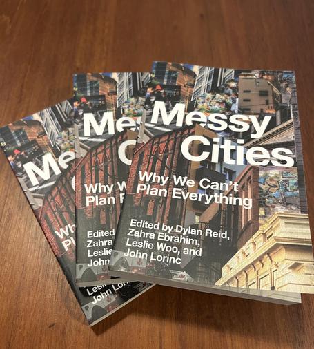 A stack of books titled "Messy Cities: Why We Can't Plan Everything," edited by Dylan Reid, Zahra Ebrahim, Leslie Woo, and John Lorinc. The covers feature urban imagery and vibrant colors. 