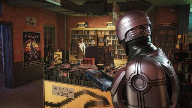 Ein Series X Screenshot mit RoboCop in einer schummrigen Videothek. Er hält eine Videokassette mit dem Titel "The Good Shepherd"  in einer Hand. Im Hintergrund steht sein zwielichtiger Informant.