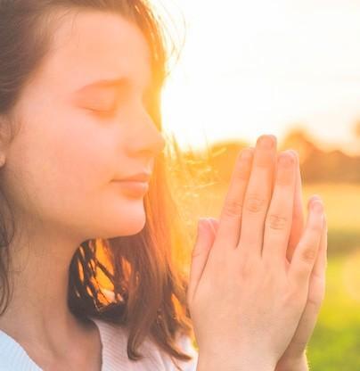 Young woman praying in the sunlight 