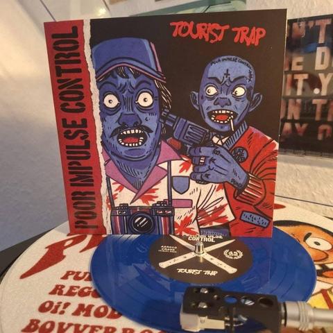 Ein Bild mit einer blauen Vinyl-Schallplatte auf einem Plattenteller, begleitet vom Album-Artwork für "Tourist Trap" von Poor Impulse Control. Das Artwork zeigt zwei cartoonartige Zombiefiguren, von denen die eine eine Kamera und die andere eine Pistole hält.