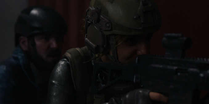 Imagem escura e tensa mostrando dois personagens do episódio Crossfire: Good Conflict, da série Secret Level. Em primeiro plano, Layla está armada com um fuzil, usando um capacete tático e colete militar, com expressão séria e concentrada. Ao fundo, Mahler aparece parcialmente desfocado, também usando equipamento tático, observando atento a movimentação ao redor. A cena sugere que estão prestes a entrar em combate ou em uma situação de alto risco.