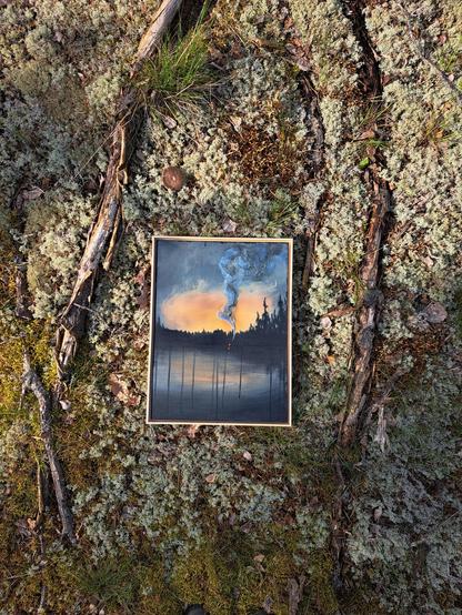 An acrylic painting on plywood with light wooden frames. The painting is placed on the ground on some lichen and moss, next to some old branches.
The painting is a scenery of a lake at sunset with trees in the horizon. In the middle of the dark horizon is a campfire that leaves a large smoke trail to the sky.