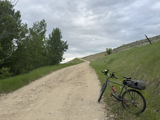 A metallic grey mountain bike at the bottom of a gravel hill