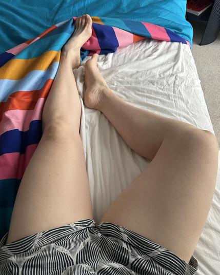Photo looking down at my legs while I lay in bed. I’m wearing black and white patterned boxer shorts and my feet are on show for the foot fetish peeps. I still think my thighs steal the show… 
