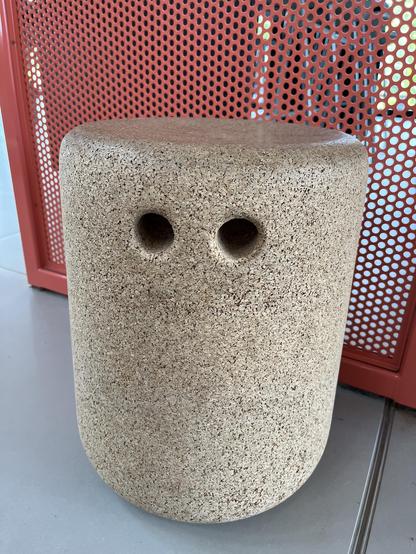 A cork stool with two finger holds in its side making a face, triggering pareidolia