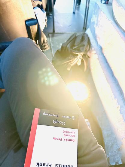 I am seated next to a very bright spotlight that shines upward from the floor. The image captures this perspective, highlighting a yellowish light with lens flares.