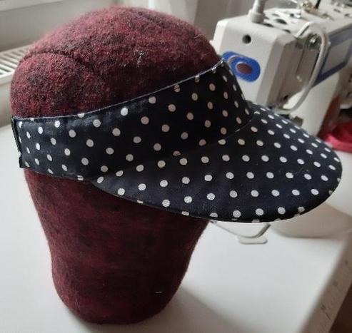 Sun visor with black and white polka dot fabric mounted on a head form.
