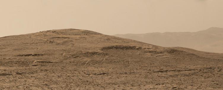 An ochre toned image capturing a Martian landscape, with the rim of Gale Crater in the background.