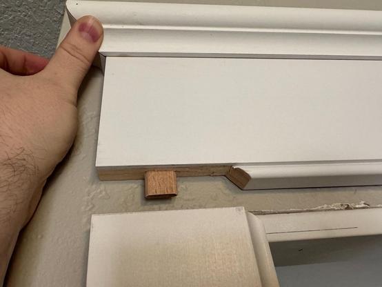 A header molding is held up to show the hidden tenon that will mate with the leg below.
