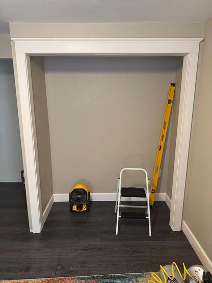 A closet door with white finish trim moldings.