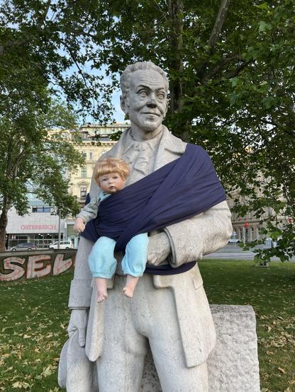 Statue eines berühmten Mannes mit einer Babypuppe in einem Tragetuch