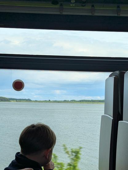 Un petit garçon regarde par la fenêtre du train sur le plan d'eau de la mer baltique