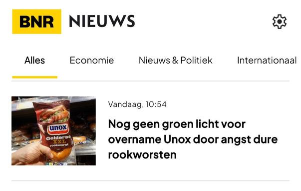 Screenshot van BNR nieuwsapp: een kop van een artikel in het overzicht van nieuwsonderwerpen. 
De tekst naast een foto van een verpakking Unox Gelderse XXL rookworst:

Vandaag, 10:54 

Nog geen groen licht voor overname Unox door angst dure rookworsten
