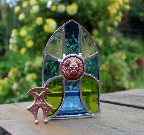 photophore représentant une croix en verre, cuivre et étain avec un médaillon lion au milieu de la croix