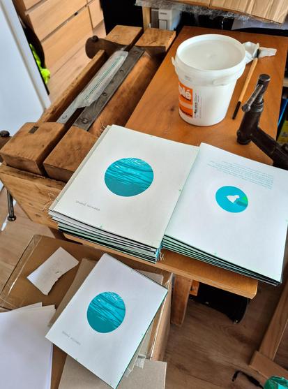 C’est une photo du plan de travail à reliure, sur lequel sont jonchés plusieurs exemplaires du nouveau livre des éditions PAPER - CUT, dont je suis membre fondatrice. Le livre est imprimé en sérigraphie et relié à la main. Ici, les couvertures ne sont pas encore posées.
