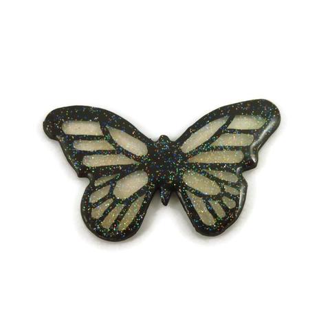 Magnet éco-responsable en forme de papillon féérique transparent et noir finement pailleté.
La perle est réalisée en CD recyclé, découpée et peinte à la main, puis recouverte de résine époxy.
