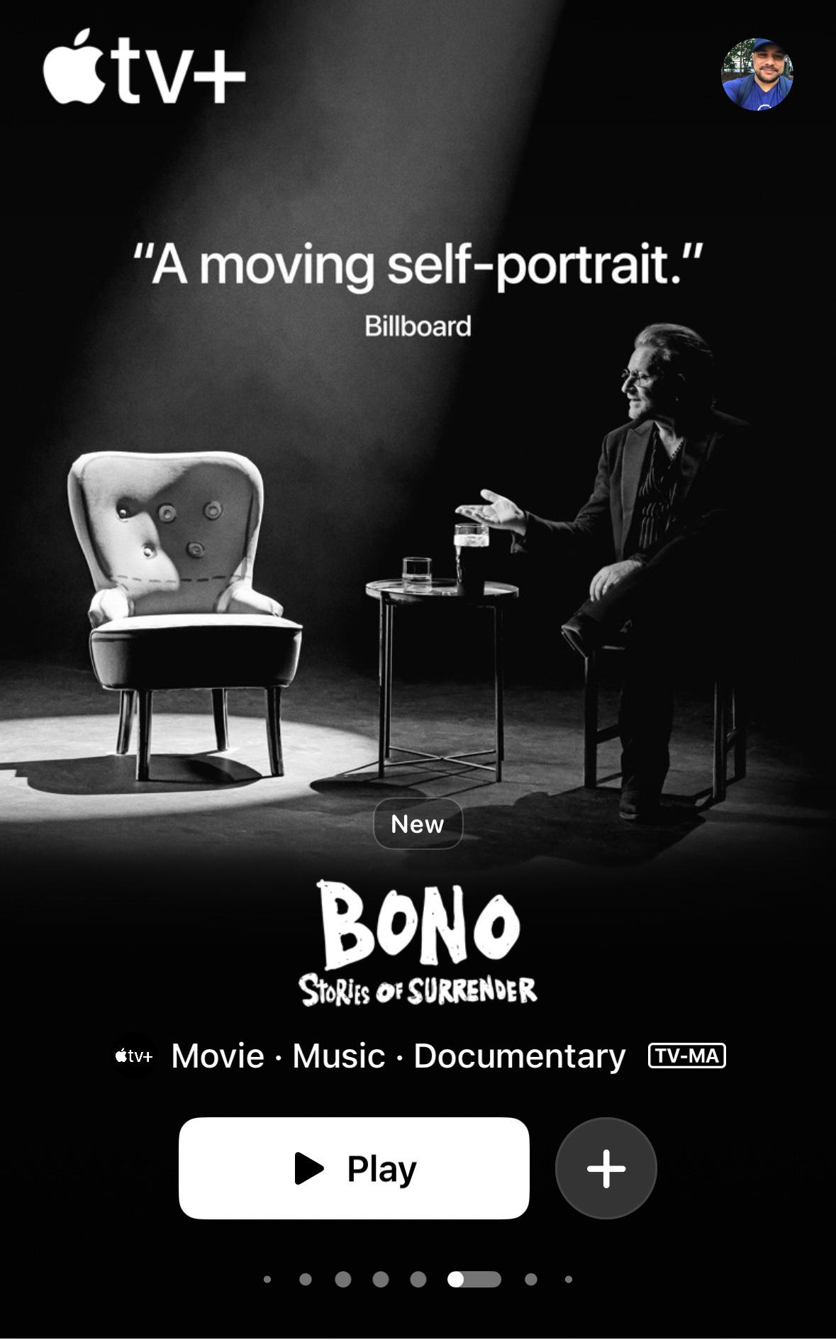 Screenshot of a documentary poster on Apple TV. Black and white. Bono is sitting. There's an empty chair adjacent to him with a table in the middle. &10;&10;"A moving self-portrait"&10;&10;Bono: Stories of Surrender &10;&10;Play button. 